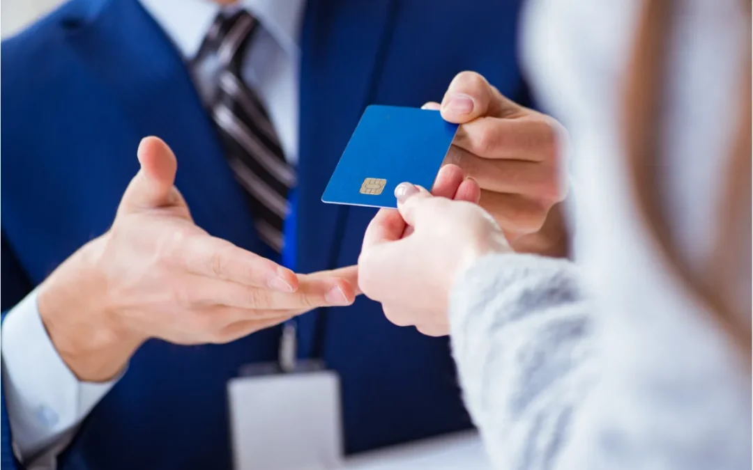A person in a blue suit handing a blue credit card to someone.