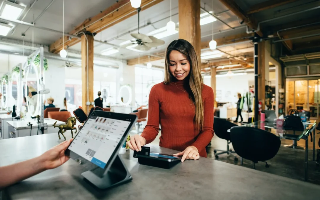 A woman in red uses a payment terminal in a bright, busy room.